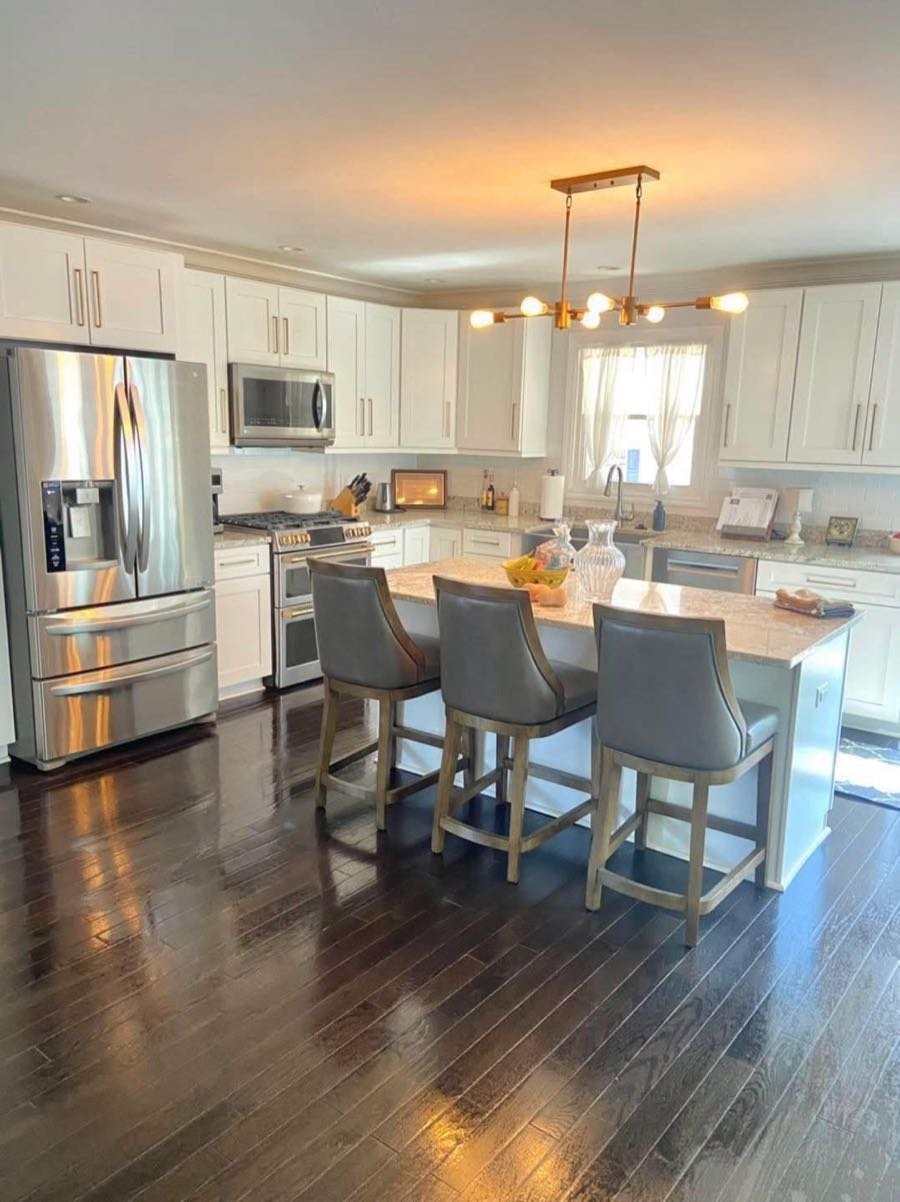 White kitchen with a granite island and gray counter stools